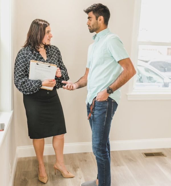 Real estate agent and client in business attire discussing a contract indoors.