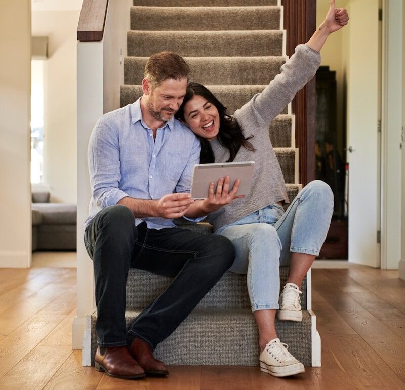 woman celebrating besides man looking at tablet